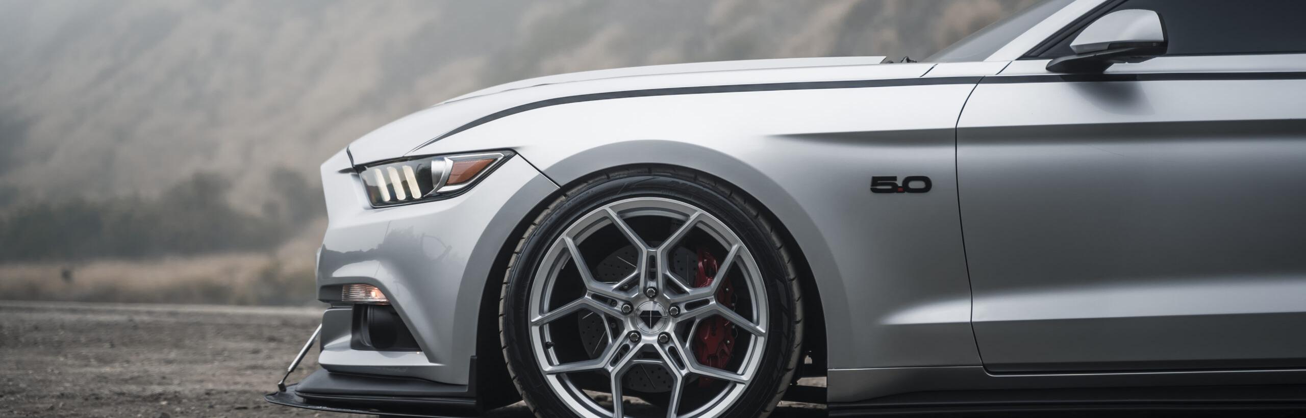header image of a silver sports car with custom rims